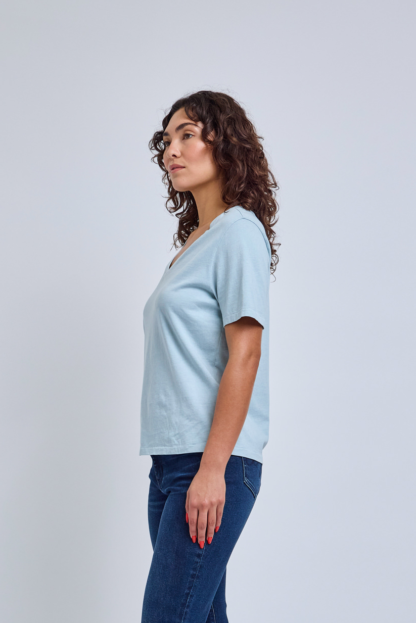 Woman wearing a light blue t-shirt and dark blue jeans against a white background