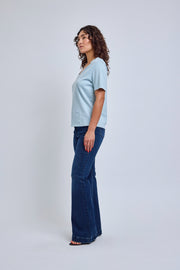 Woman wearing a light blue t-shirt and dark blue jeans on a white background
