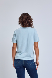 Person wearing a light blue t-shirt and dark blue jeans on a plain background