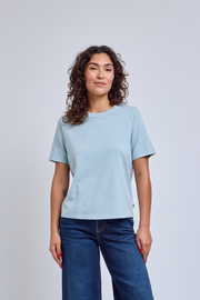 Woman wearing a light blue t-shirt and blue jeans against a plain background | model-size: 4