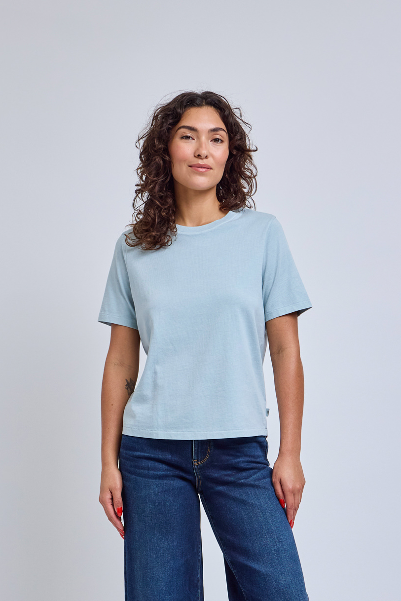 Woman wearing a light blue t-shirt and blue jeans against a plain background | model-size: 4
