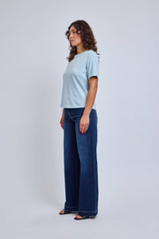 Woman wearing a light blue t-shirt and dark blue jeans on a white background