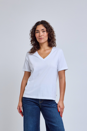 Woman wearing a plain white t-shirt and blue jeans against a light gray background