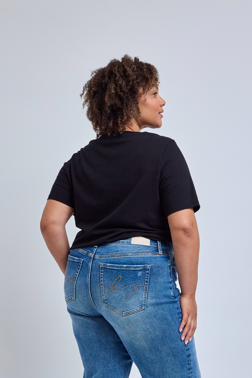 Person wearing a black t-shirt and blue jeans on a light gray background