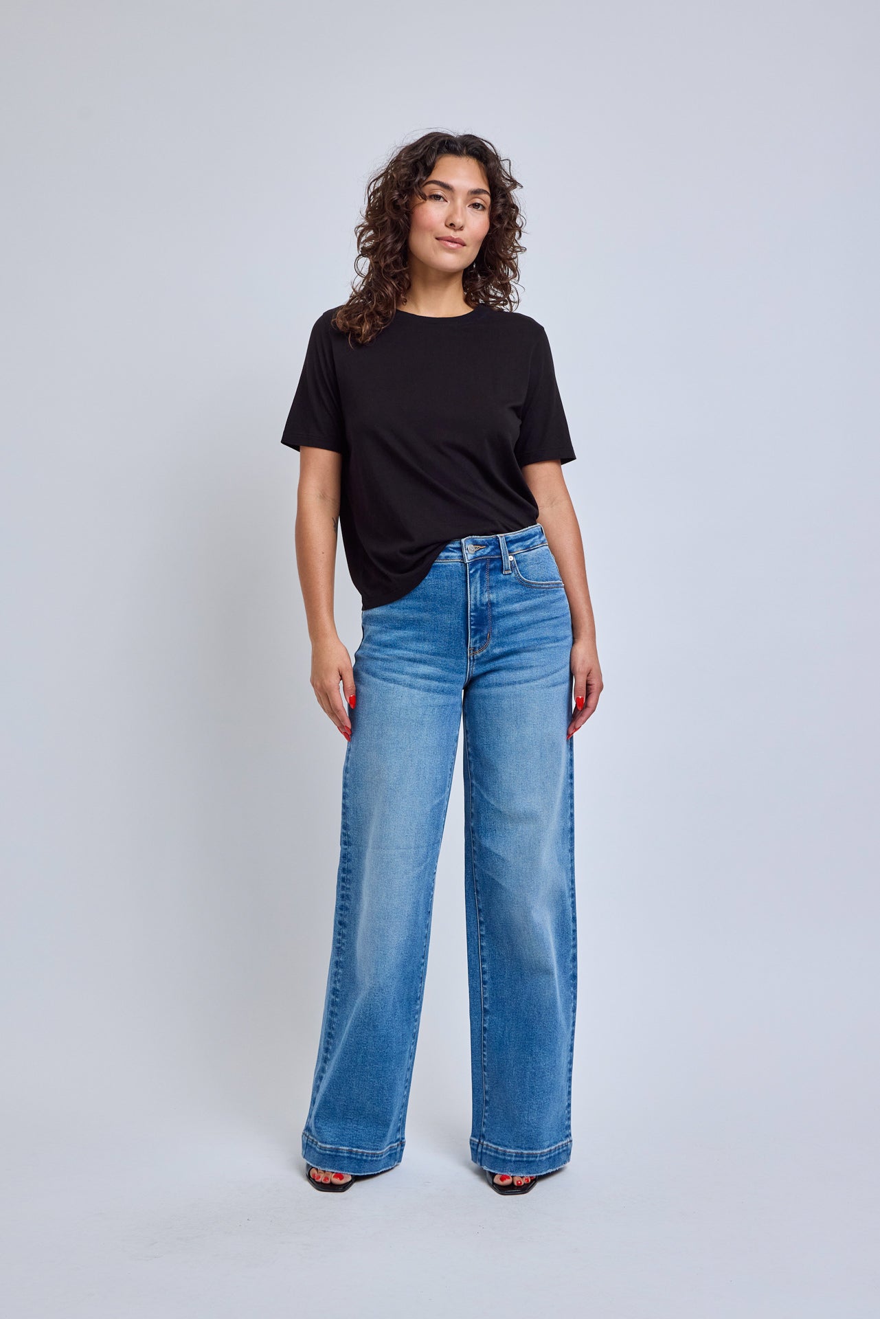 Person wearing a black t-shirt and blue jeans on a white background | model-size: 4