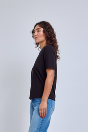 Woman wearing a black t-shirt and blue jeans against a light gray background