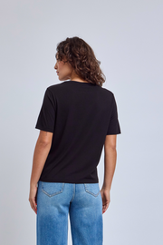 Person wearing a black t-shirt and blue jeans on a light gray background