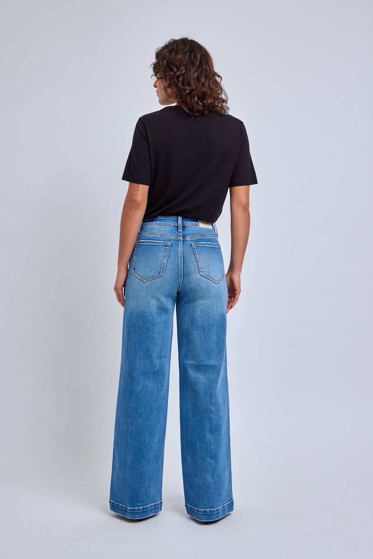 Person wearing blue jeans and a black t-shirt on a white background