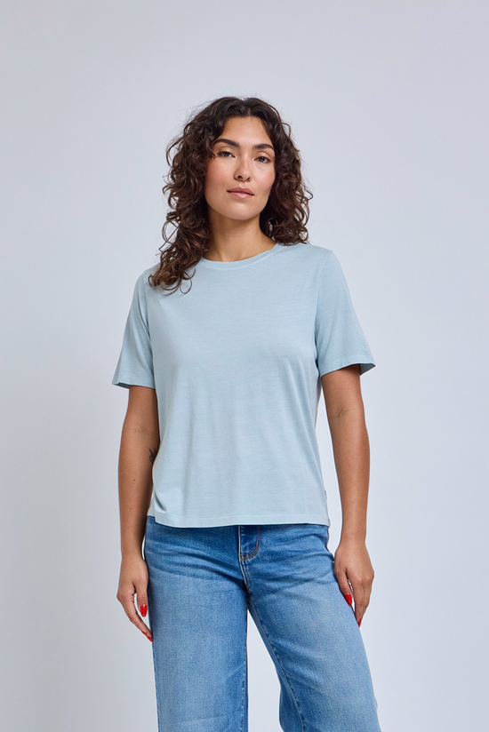 Woman wearing a light blue t-shirt and blue jeans against a plain background | model-size: 4