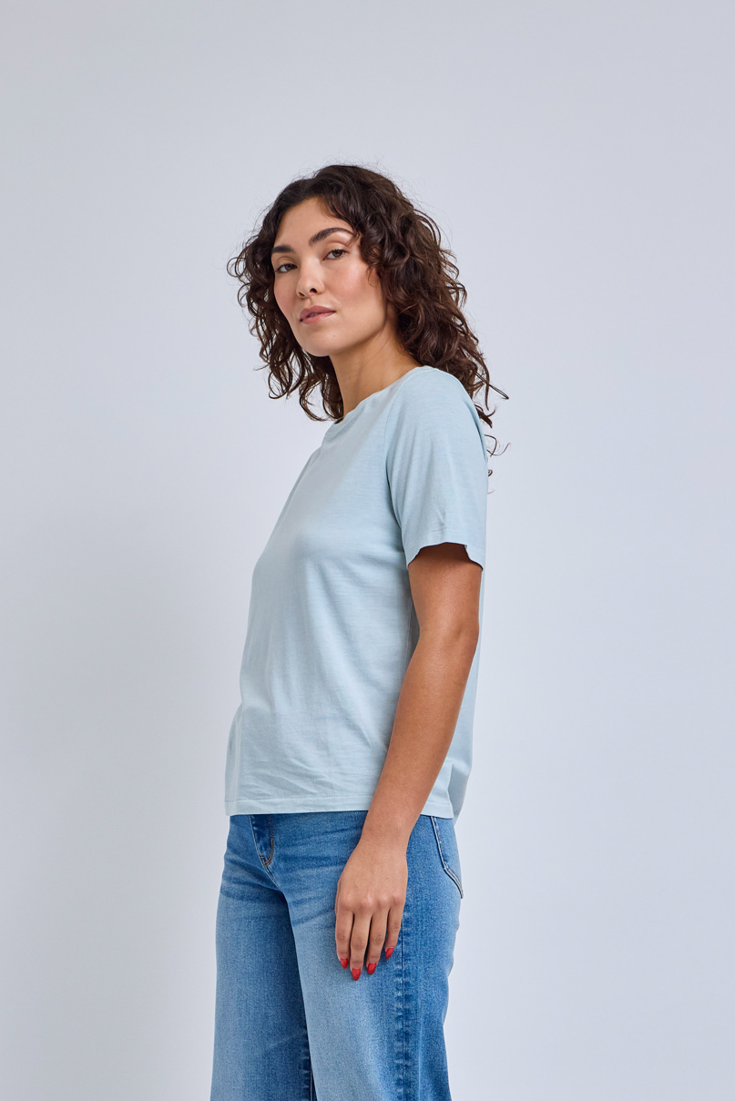 Woman wearing a light blue t-shirt and jeans on a white background