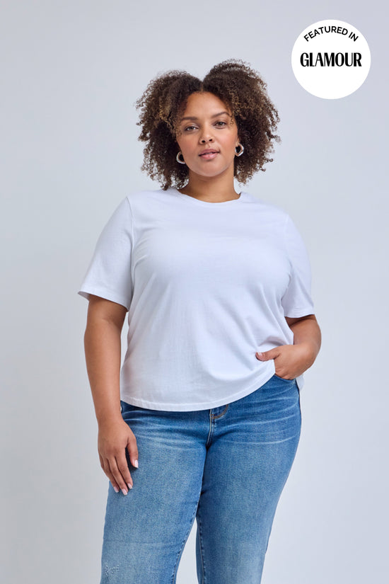 Person wearing a plain white t-shirt and blue jeans on a light gray background | model-size: 16