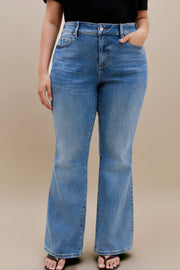 Woman wearing black t-shirt and bootcut jeans with a beige background