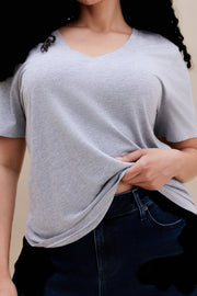 Close up of a woman wearing a heather grey v-neck t-shirt and dark jeans