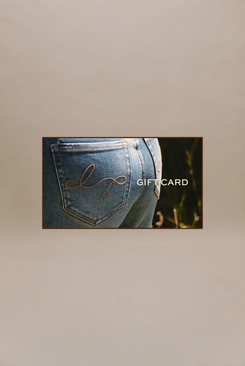 A rectangular gift card featuring a close-up photo of the back pocket of blue jeans with gold contrast stitching and a small embroidered logo, plus the text 'GIFT CARD' on the right. The card is centered on a plain beige background.