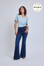 Woman wearing a light blue t-shirt and dark blue jeans on a white background.