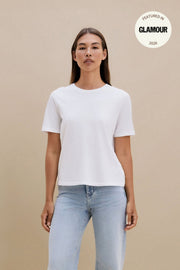 Woman wearing a plain white t-shirt and blue jeans against a beige background | model-size: 4