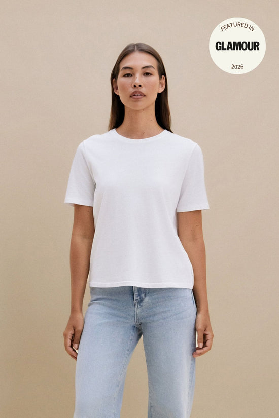 Woman wearing a plain white t-shirt and blue jeans against a beige background | model-size: 4