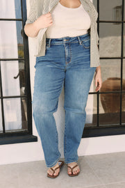 Person wearing blue jeans and a striped shirt standing indoors.