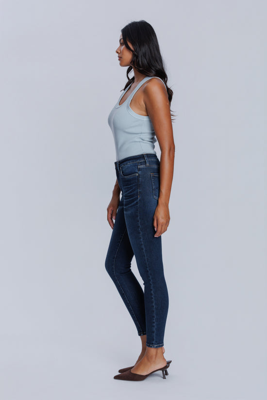 Woman wearing a DePart light blue tank top and dark blue skinny jeans against a light gray background