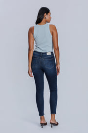 Woman wearing a DePart light blue tank top and dark blue skinny jeans against a light gray background