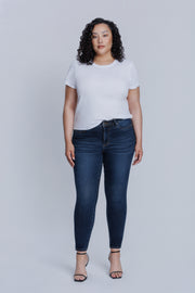 Woman wearing a DePart white tee and dark blue skinny jeans against a light gray background | model-size: 16