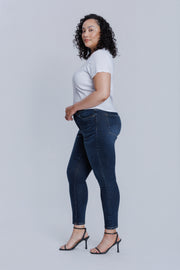 Woman wearing a DePart white tee and dark blue skinny jeans against a light gray background