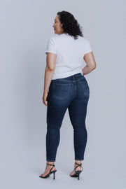 Woman wearing a DePart white tee and dark blue skinny jeans against a light gray background