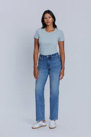 Woman wearing a DePart light blue tee and blue jeans against a plain background | model-size: 4