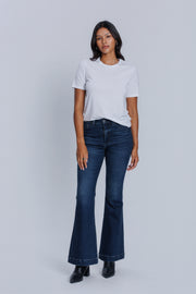 Woman wearing a DePart white crew neck t-shirt and dark blue jeans against a light gray background | model-size: 4