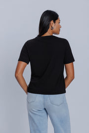 Woman wearing a DePart black t-shirt and light blue jeans against a light gray background