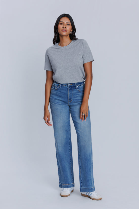 Woman wearing a DePart gray crew neck t-shirt and blue jeans against a light gray background | model-size: 4
