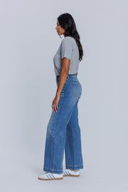 Woman wearing a DePart gray crew neck t-shirt and blue jeans against a light gray background