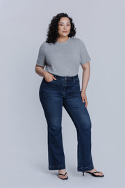 Woman wearing a DePart gray crew neck t-shirt and dark blue jeans against a light gray background | model-size: 16