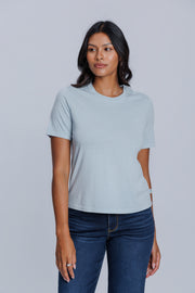 Woman wearing a DePart light blue t-shirt and dark blue jeans against a light gray background | model-size: 4