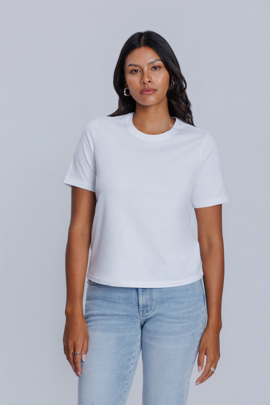 Woman wearing a DePart white t-shirt and light blue jeans against a light gray background | model-size: 4