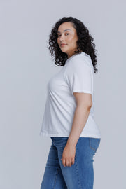 Woman wearing a DePart white t-shirt and blue jeans against a light gray background