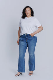 Woman wearing a DePart white t-shirt and blue flare jeans against a light gray background | model-size: 16