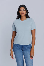 Woman wearing a DePart light blue t-shirt and blue jeans against a light gray background | model-size: 4
