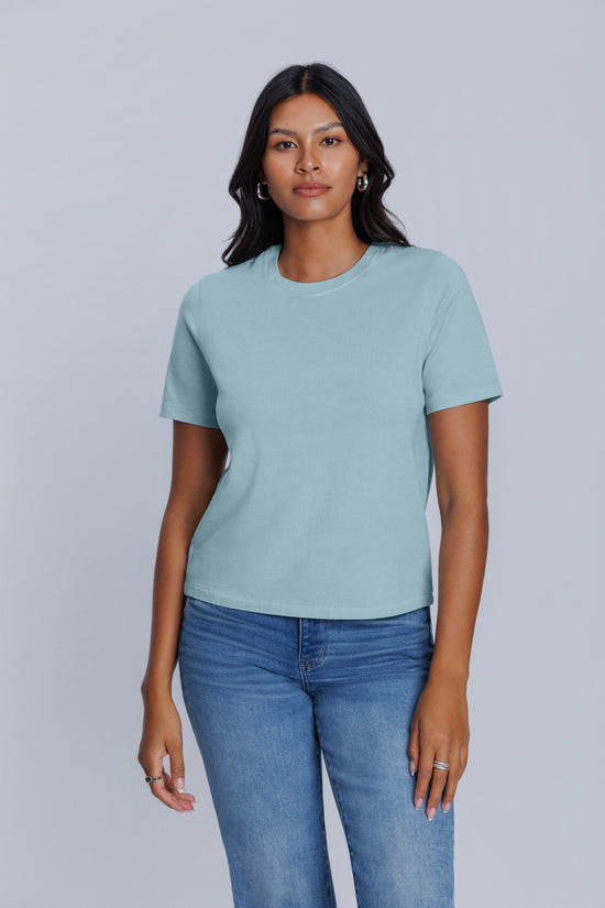 Woman wearing a DePart light blue t-shirt and blue jeans against a light gray background | model-size: 4