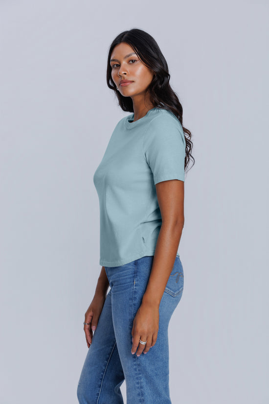 Woman wearing a light blue t-shirt and jeans on a plain background