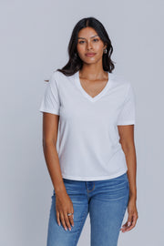 Woman wearing a DePart white t-shirt and blue skinny jeans against a light gray background | model-size: 4