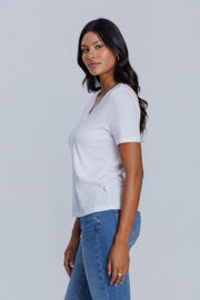 Woman wearing a DePart white t-shirt and blue skinny jeans against a light gray background