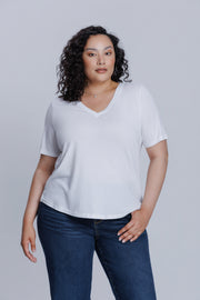 Woman wearing a DePart white t-shirt and dark blue skinny jeans against a light gray background | model-size: 16