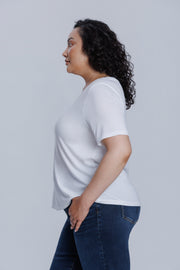 Woman wearing a plain white t-shirt and dark blue jeans against a light gray background