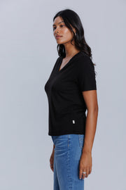 Woman wearing a DePart black t-shirt and blue skinny jeans against a light gray background