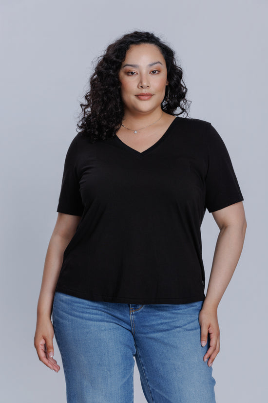 Woman wearing a DePart black t-shirt and blue skinny jeans against a light gray background | model-size: 16