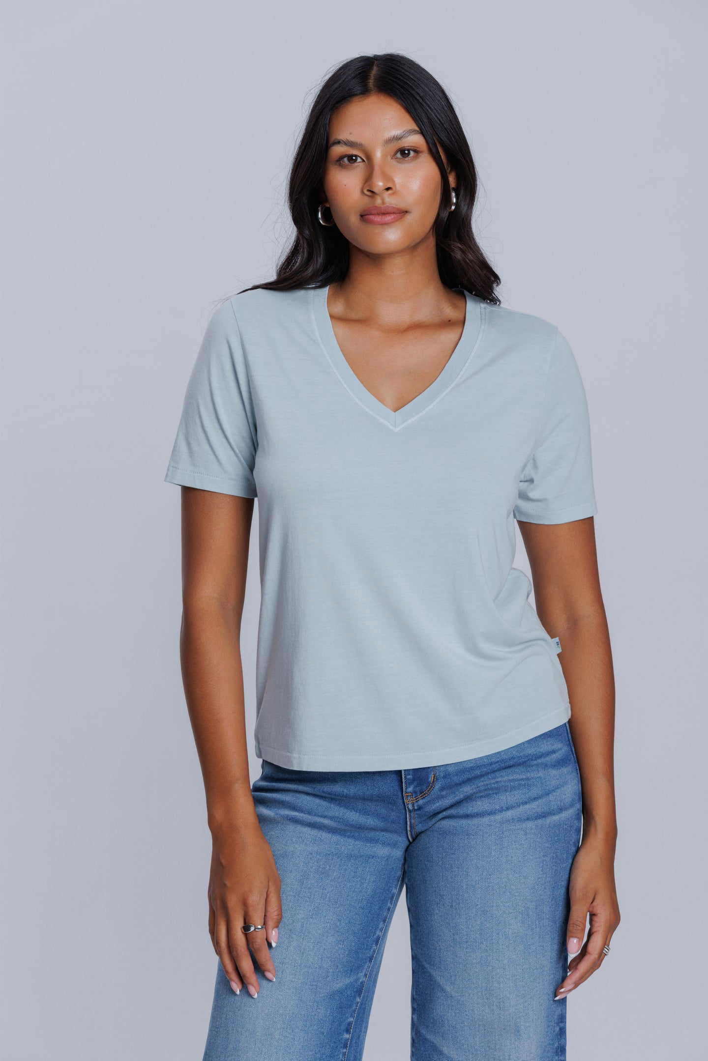 Woman wearing a DePart light blue t-shirt and lblue straight jeans against a light gray background | model-size: 4