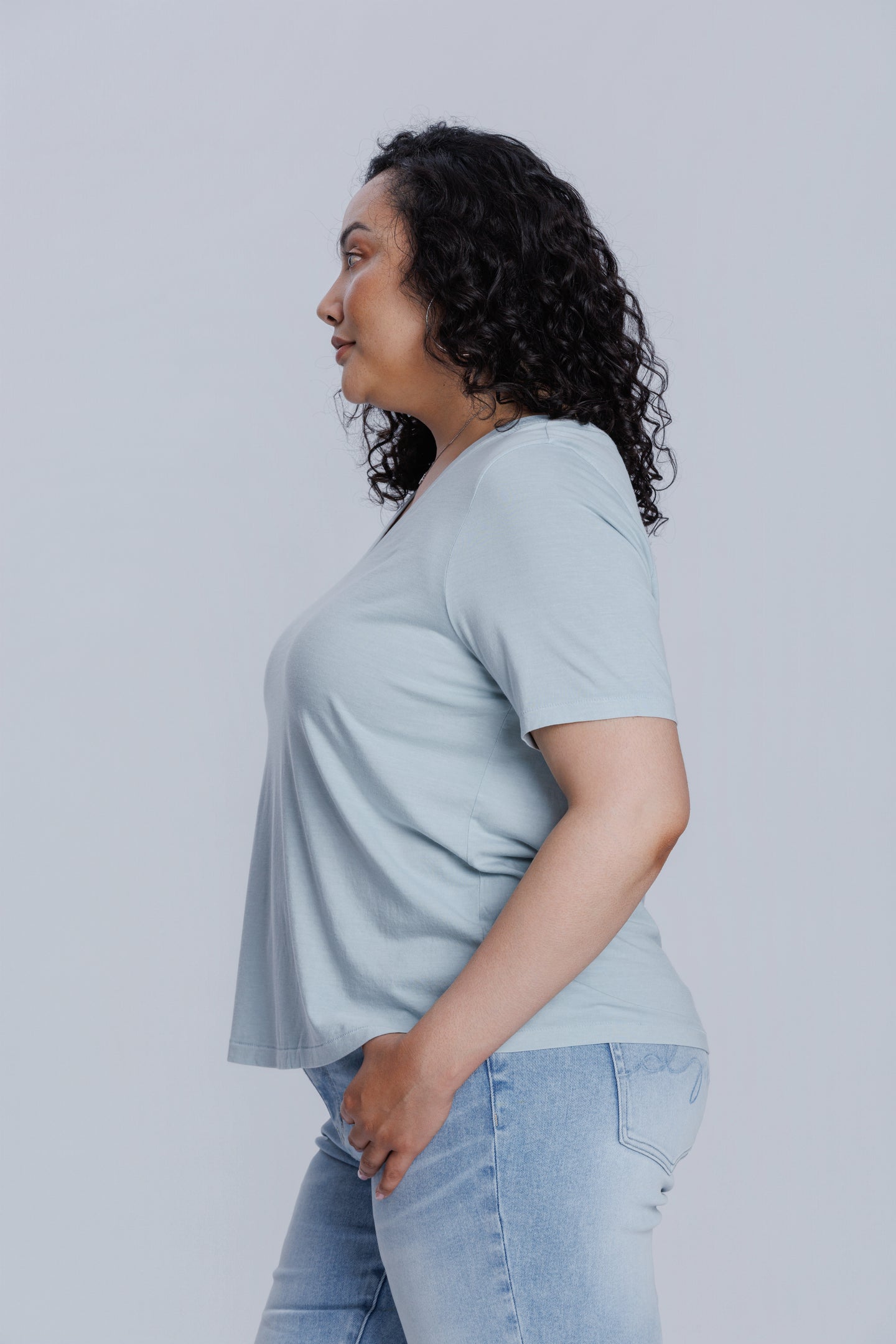 Woman wearing a DePart light blue t-shirt and light blue skinny jeans against a light gray background
