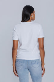 Woman wearing a DePart white t-shirt and light blue jeans against a light gray background