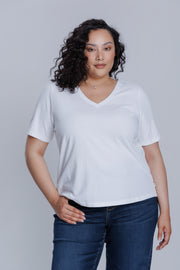 Woman wearing a DePart white t-shirt and dark blue wide leg jeans against a light gray background | model-size: 16
